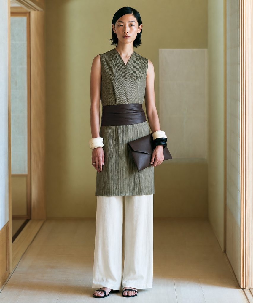A sage sleeveless wrap top cinched with a wide brown leather sash belt over white wide-leg trousers, creating a defined waist on a rectangle figure